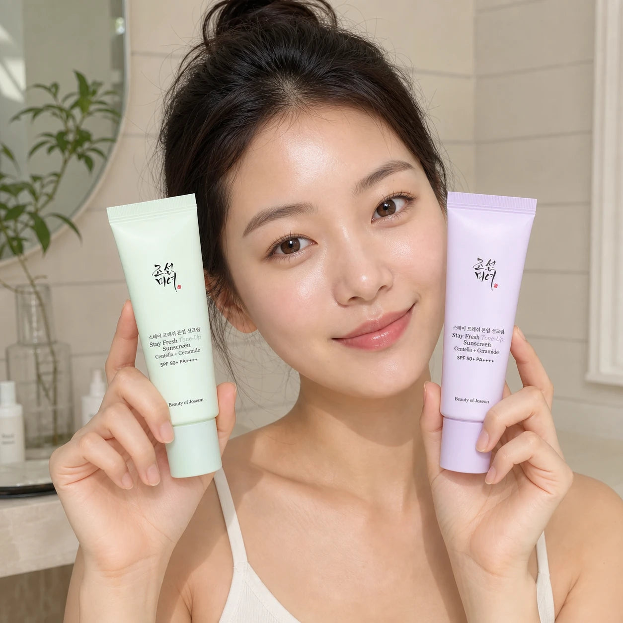 Woman holding Beauty of Joseon Stay Fresh Tone-Up Sunscreen Green and Purple tubes