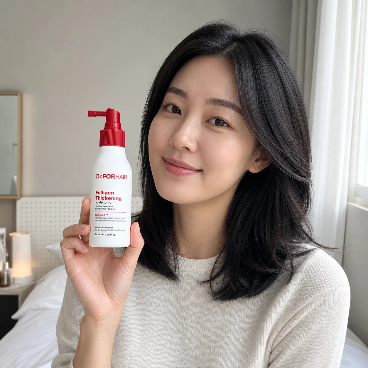 Adult woman holding Dr.FORHAIR Folligen Thickening Scalp Tonic 120ml beside her face