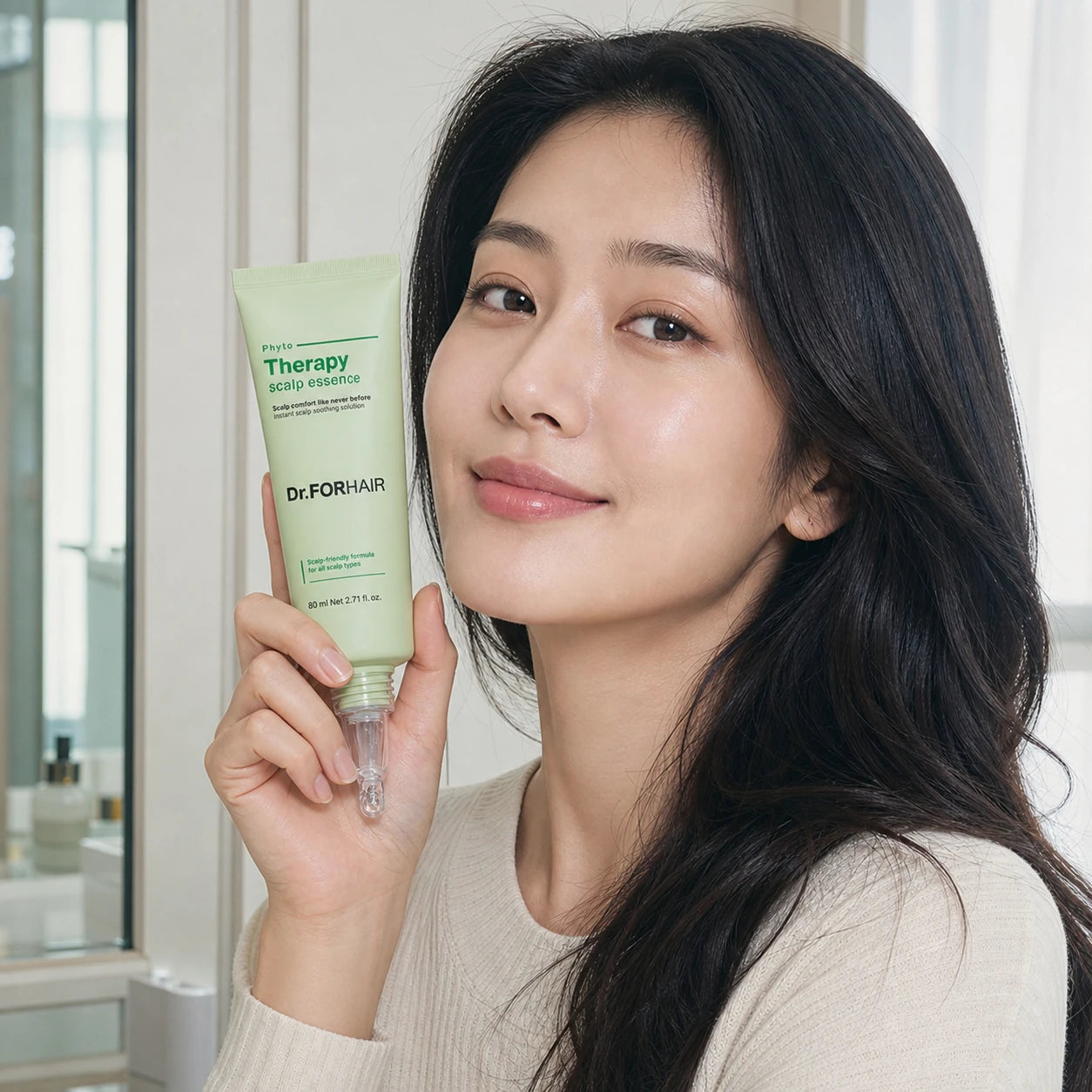 Woman holding Dr.FORHAIR Phyto Therapy Scalp Essence 80ml beside her face