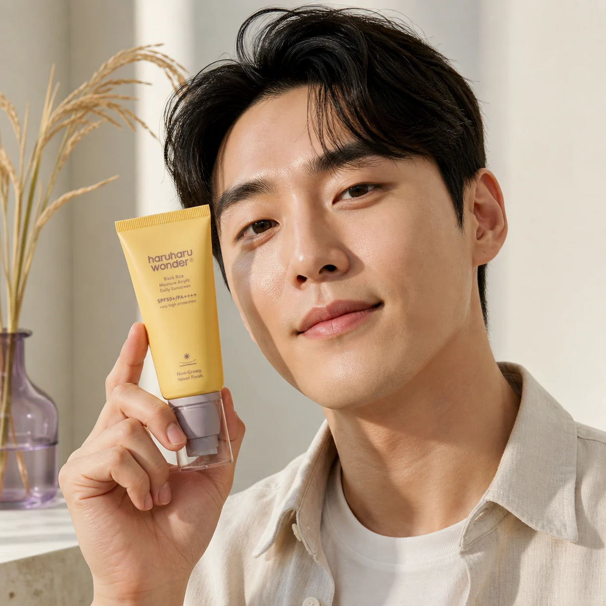Man holding haruharu wonder Black Rice Moisture Airyfit Daily Sunscreen beside his face