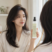 Woman holding CHAHONG Fix Volume Hair Spray beside her dark hair in a home styling space