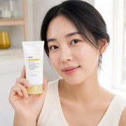 Woman holding Dear, Klairs All-day Airy Sunscreen SPF50+ PA++++ beside her cheek