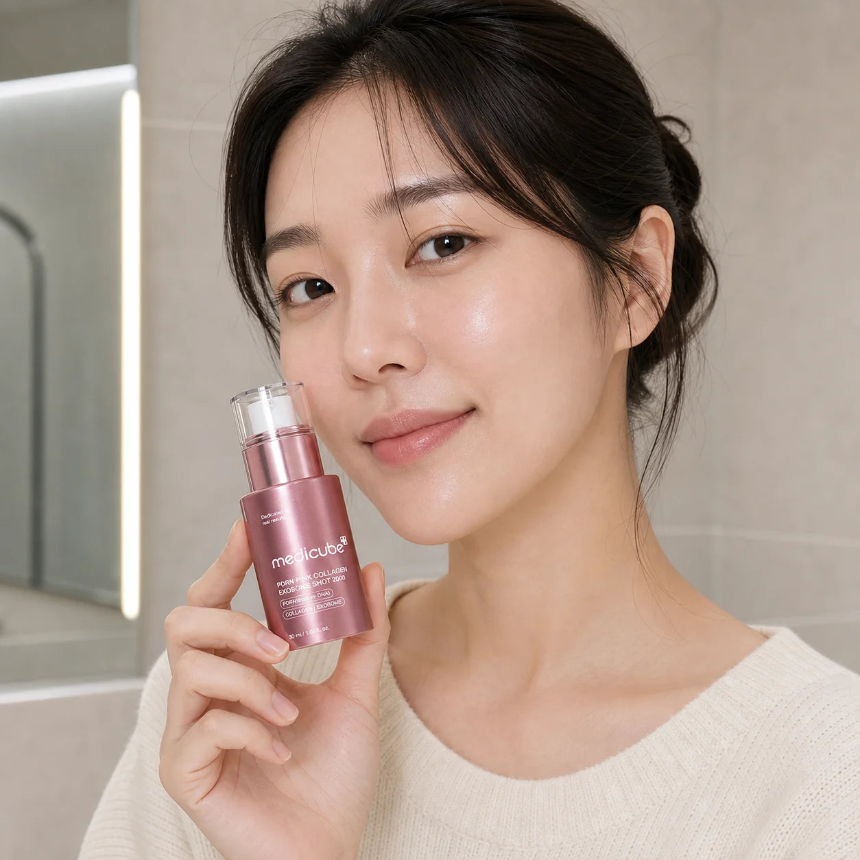 Woman holding medicube PDRN Pink Collagen Exosome Shot 2000 30ml beside her cheek