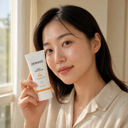 Woman holding ZEROID Daily Sun Cream SPF50+ PA++++ 50ml beside her cheek