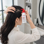 Adult woman parting her hair and applying Dr.FORHAIR Folligen Thickening Scalp Tonic to the scalp