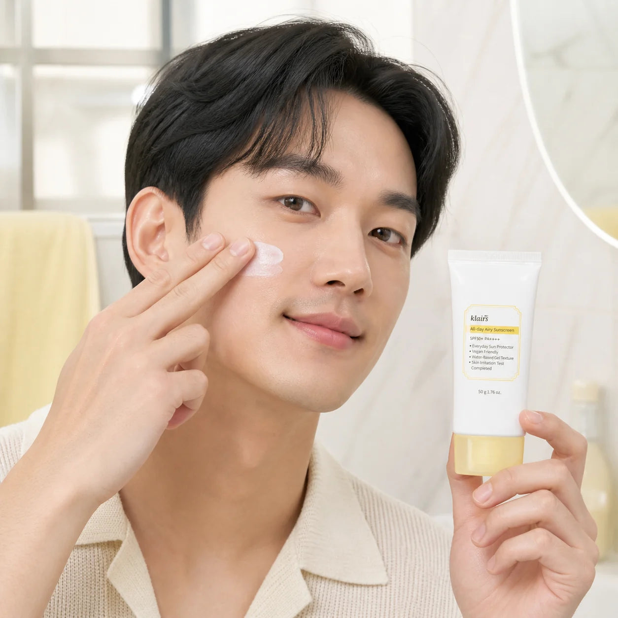 Man applying Dear, Klairs All-day Airy Sunscreen to his cheek