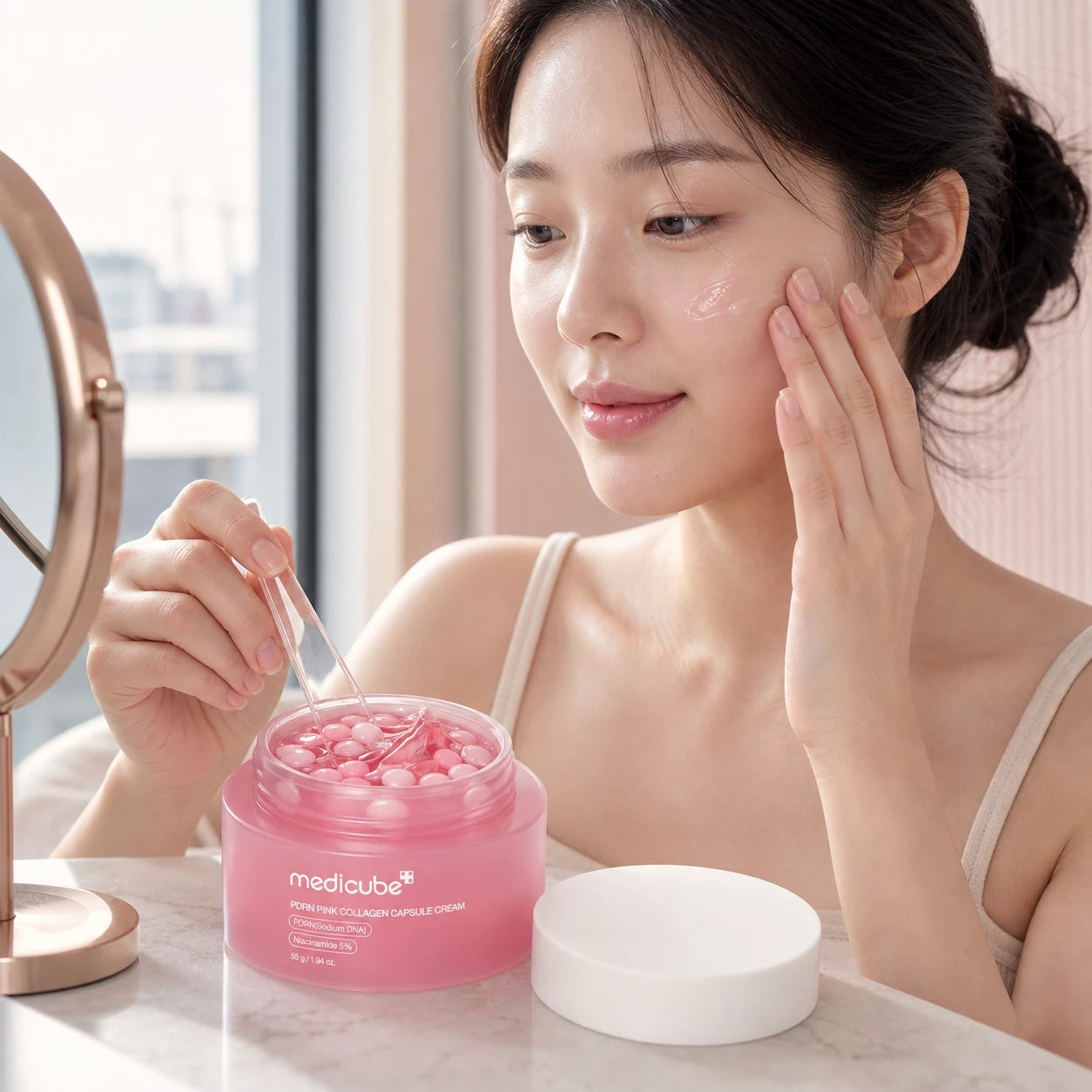 Woman blending and applying medicube PDRN Pink Collagen Capsule Cream at a vanity