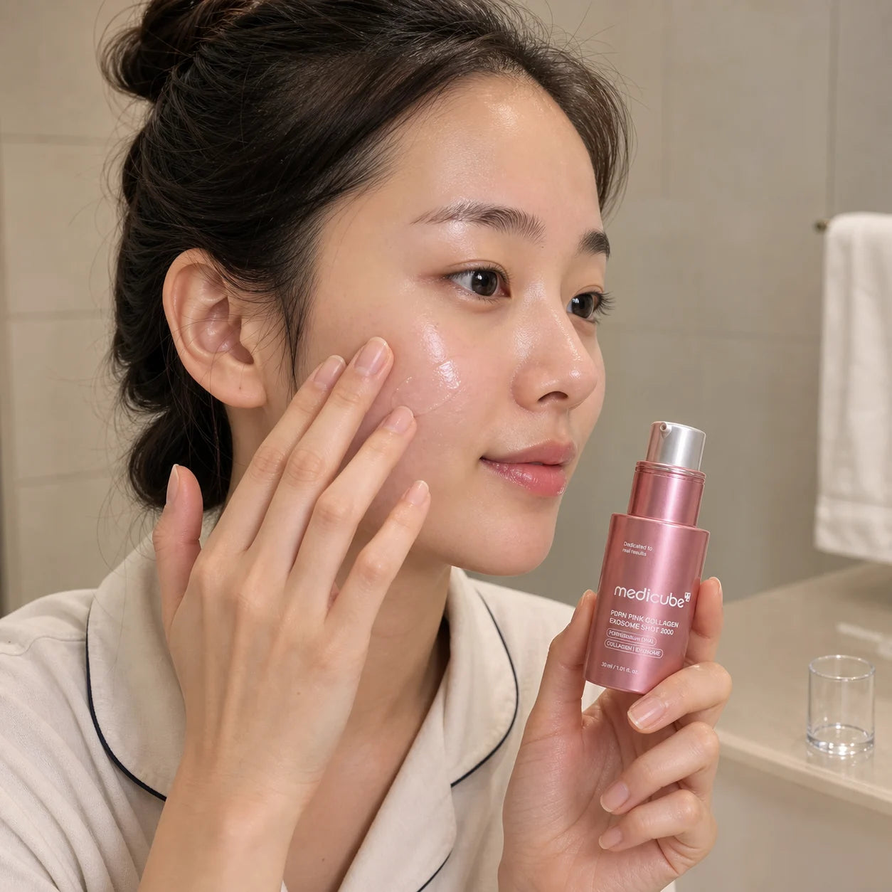Woman pressing medicube PDRN Pink Collagen Exosome Shot 2000 serum onto her outer cheek
