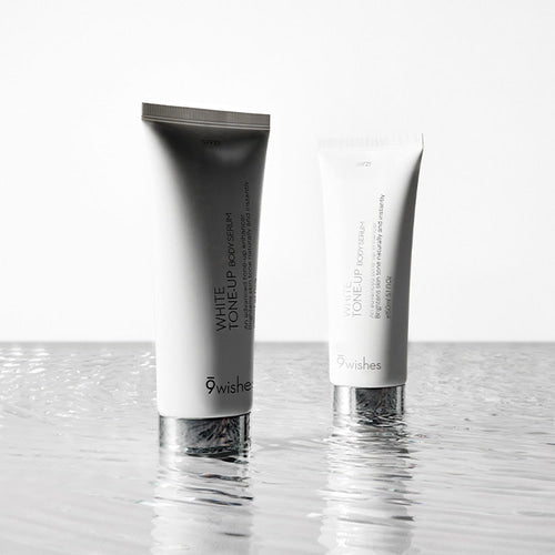 Two 9wishes White Tone-Up Body Serum SPF21 150ml tubes on reflective water