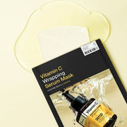 ProtoClinical k-beauty MEDIHEAL Vitamin C Wrapping Serum Mask 25ml X 10ea wide flat-lay package with a dark central panel, warm beige lower section, and pale yellow background