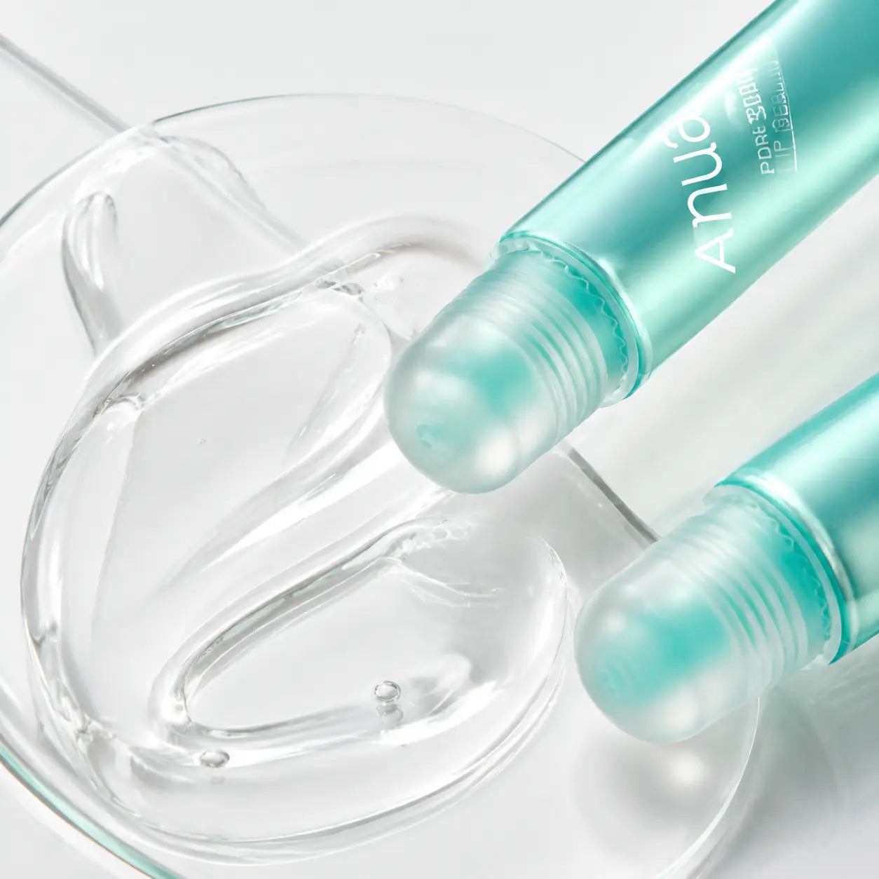 Macro view of the clear glossy texture and rounded applicators of Anua PDRN Lip Serum