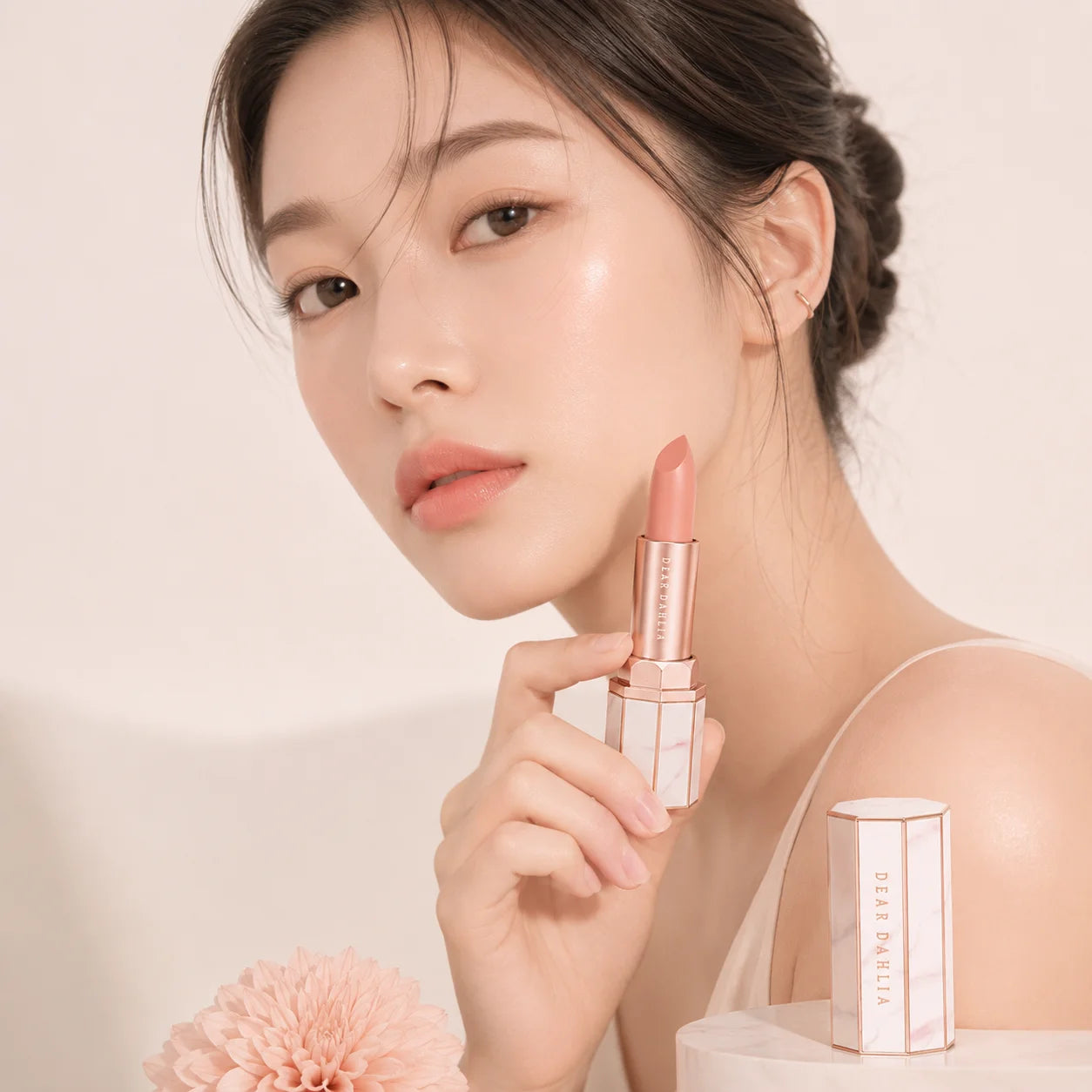 ProtoClinical k-beauty [DEAR DAHLIA] Blooming Edition Lip Paradise Sheer Dew Tinted Lipstick 3.4g close-up of a nude peach lipstick bullet in a slim beige tube on a pale blush background