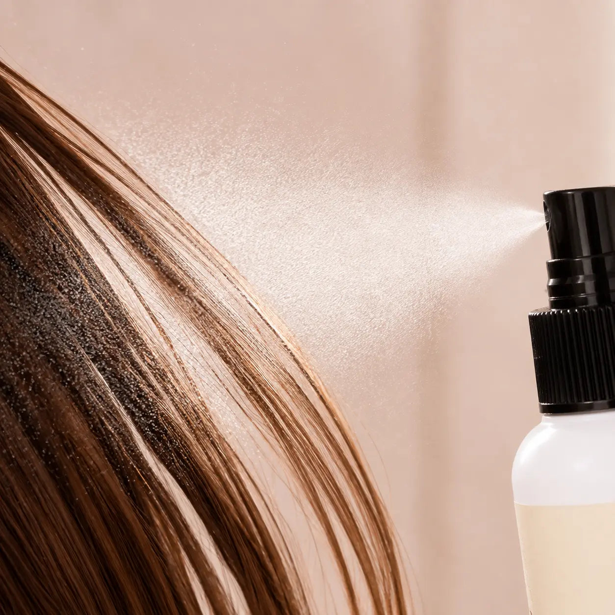 Macro view of the fine CHAHONG Fix Volume Hair Spray mist crossing separated brown hair strands