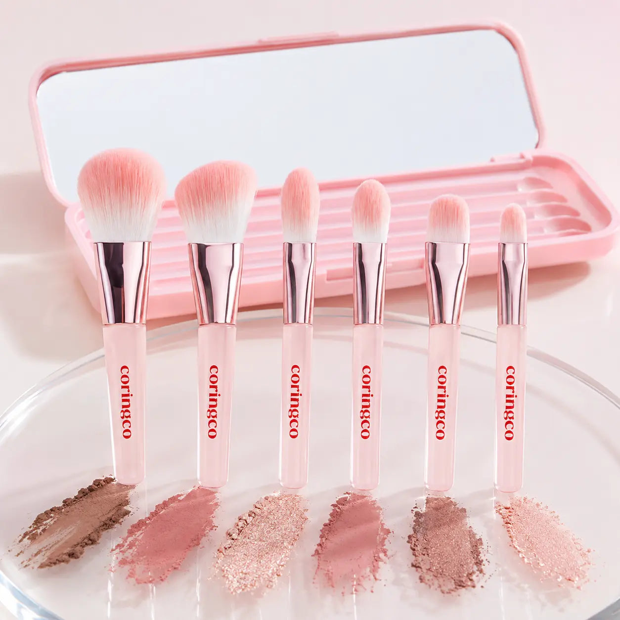 Six CORINGCO Pink Pocket Eye Brush heads with eye makeup swatches