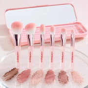 Six CORINGCO Pink Pocket Eye Brush heads with eye makeup swatches