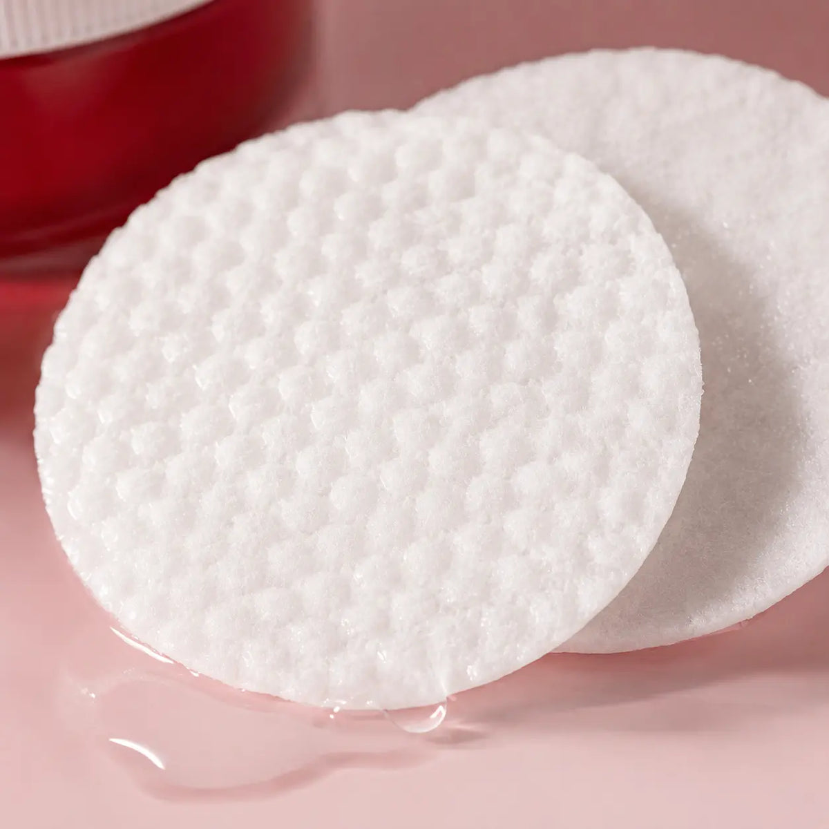 Macro view of embossed and smooth COSRX toner pad sides soaked with clear watery essence