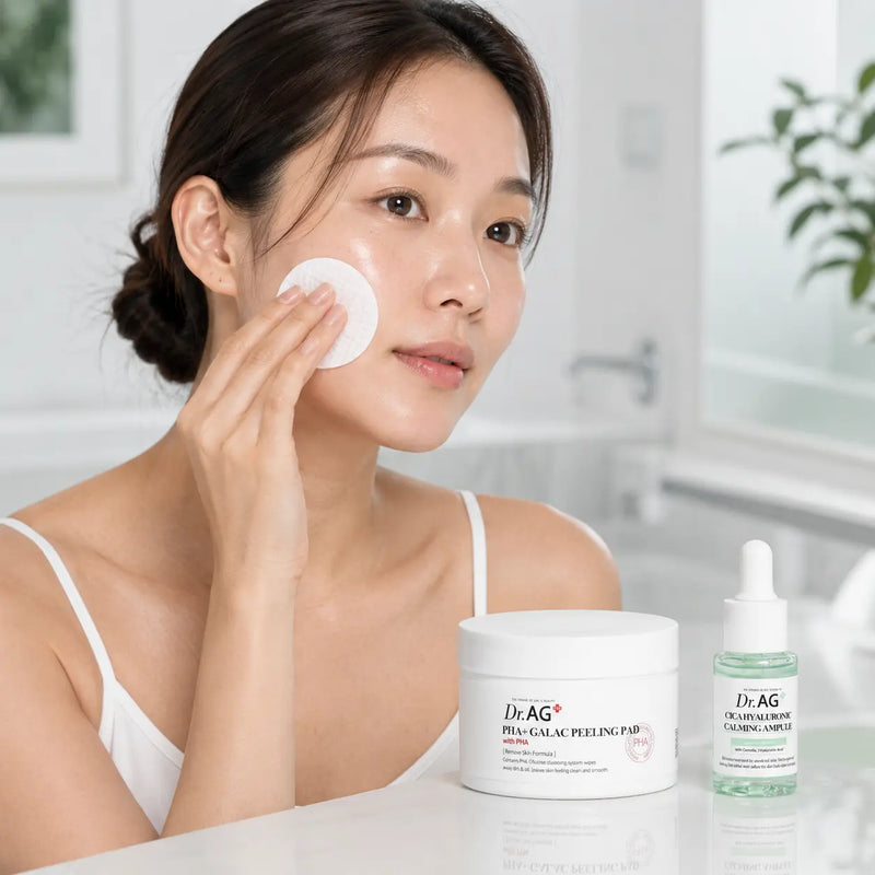 Model gently sweeping a PHA peeling pad across the cheek beside the Dr.AG+ set