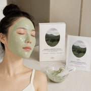 Woman wearing a soft sage-green Dr.Althea Cica modeling mask during an at-home spa routine