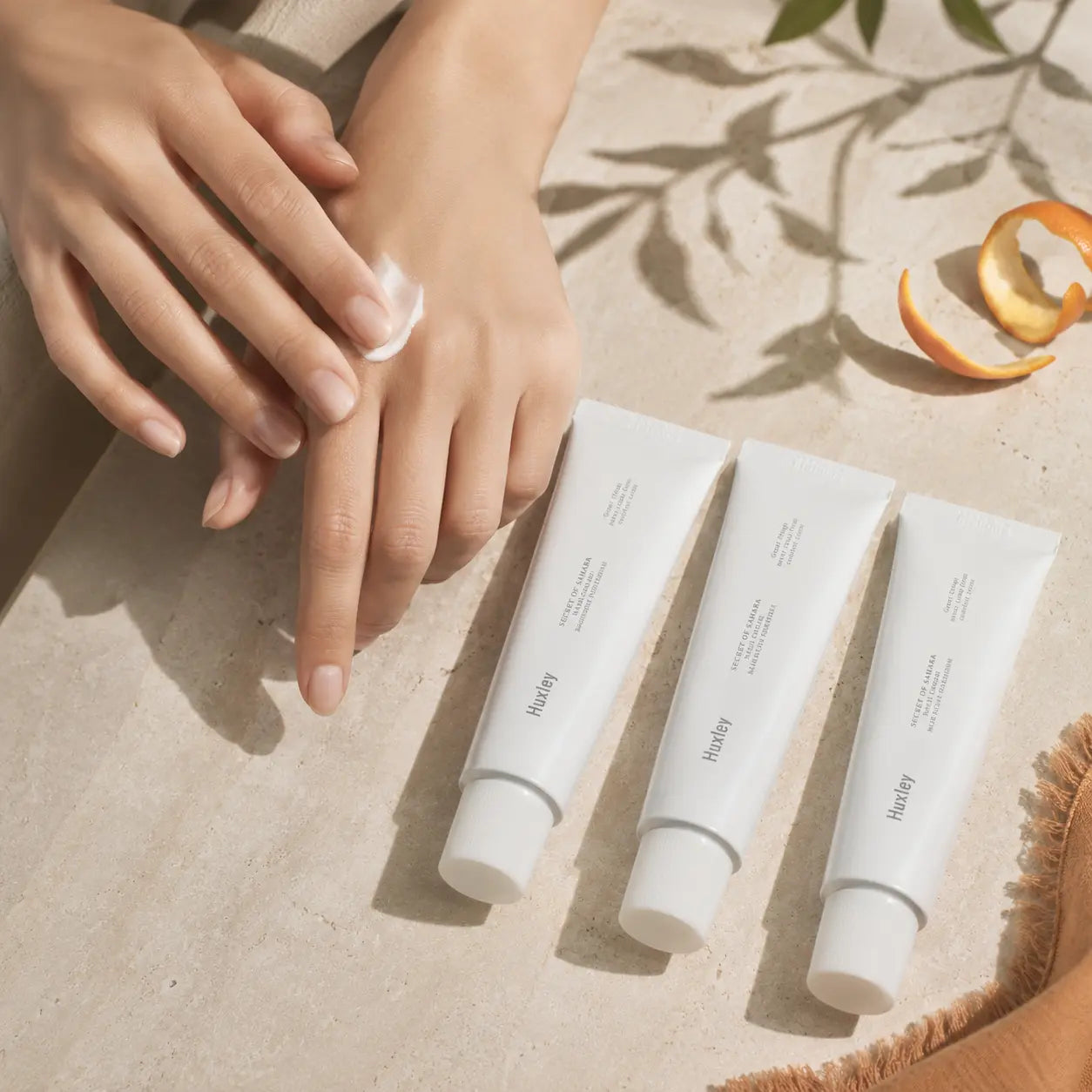 Huxley Hand Cream Trio beside hands applying cream
