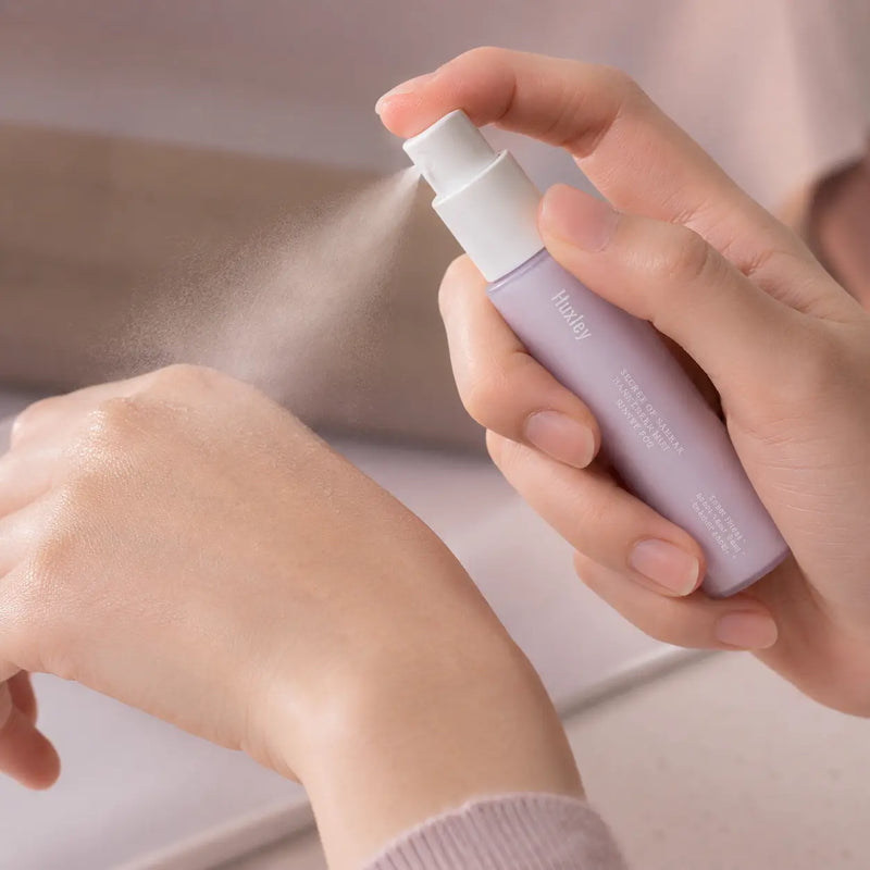 Huxley Sunset Fog hand cream mist sprayed onto the back of a hand