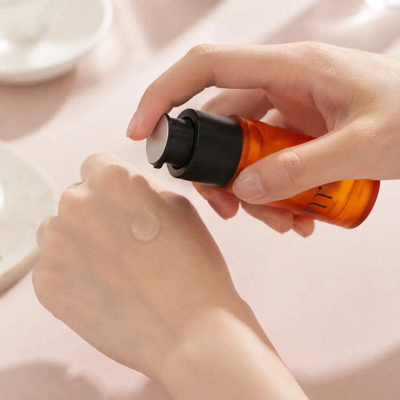Clear Molvany Vitamin C 15% Ampoule serum dispensed from the orange pump bottle onto the back of a hand