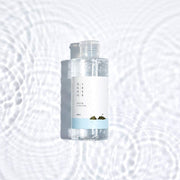ProtoClinical k-beauty Round Lab 1025 Dokdo Toner 200ml abstract beauty graphic with soft mint, peach, and violet tones on a pale background.