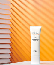 ProtoClinical k-beauty IOPE UV Shield Essential Sun Protector SPF 50+ PA++++ 50ml shown as a single slim sun-protector package on a warm beige and amber background