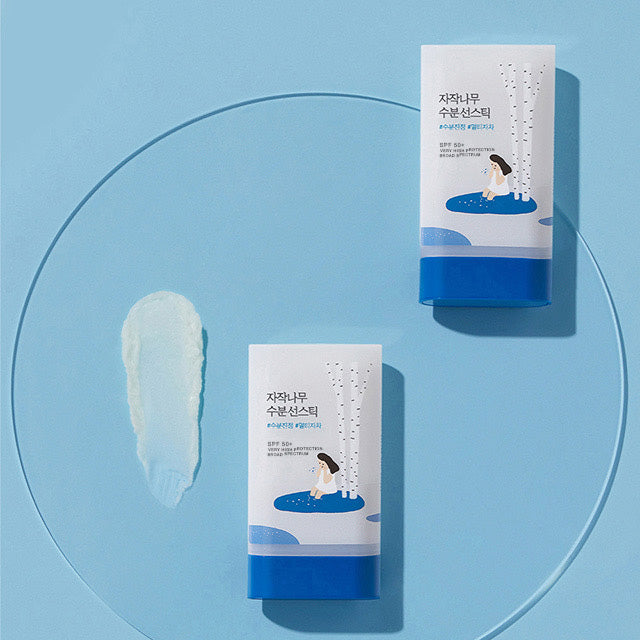 ProtoClinical k-beauty Round Lab Birch Juice Moisturizing Sun Stick 19g (SPF 50+ PA++++) two white sun stick packages beside a white cream swatch on a round light blue tray