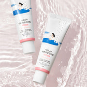 ProtoClinical k-beauty Round Lab Birch Juice Moisturizing Tone Up Sunscreen 50ml (SPF 50+ PA++++) two white sunscreen tubes laid diagonally on a rippled pale pink background
