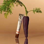 ProtoClinical k-beauty goodal Black Carrot Vita-A Retinol Eye Cream 30ml shown as an ivory eye cream tube leaning beside a dark purple carrot on a warm beige background