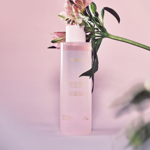 ProtoClinical k-beauty Huxley Skin Glow Toner Vita Radiance 200ml mauve package silhouette on a soft pink and gray background.
