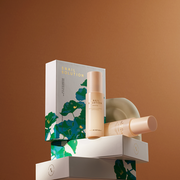 ProtoClinical k-beauty dark green product packaging centered on a warm brown background.