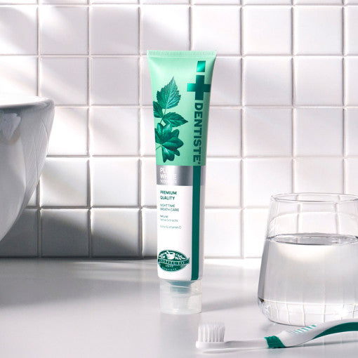 ProtoClinical k-beauty DENTISTE New Plus White Toothpaste 60g single upright teal toothpaste package centered on a light background with soft peach side accents.