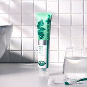 ProtoClinical k-beauty DENTISTE New Plus White Toothpaste 60g single upright teal toothpaste package centered on a light background with soft peach side accents.