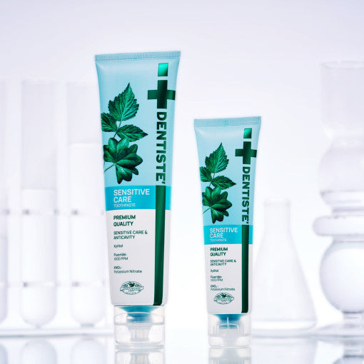 ProtoClinical k-beauty DENTISTE Sensitive Care Toothpaste 60g single upright blue toothpaste tube centered on a white background with soft pink side accents.