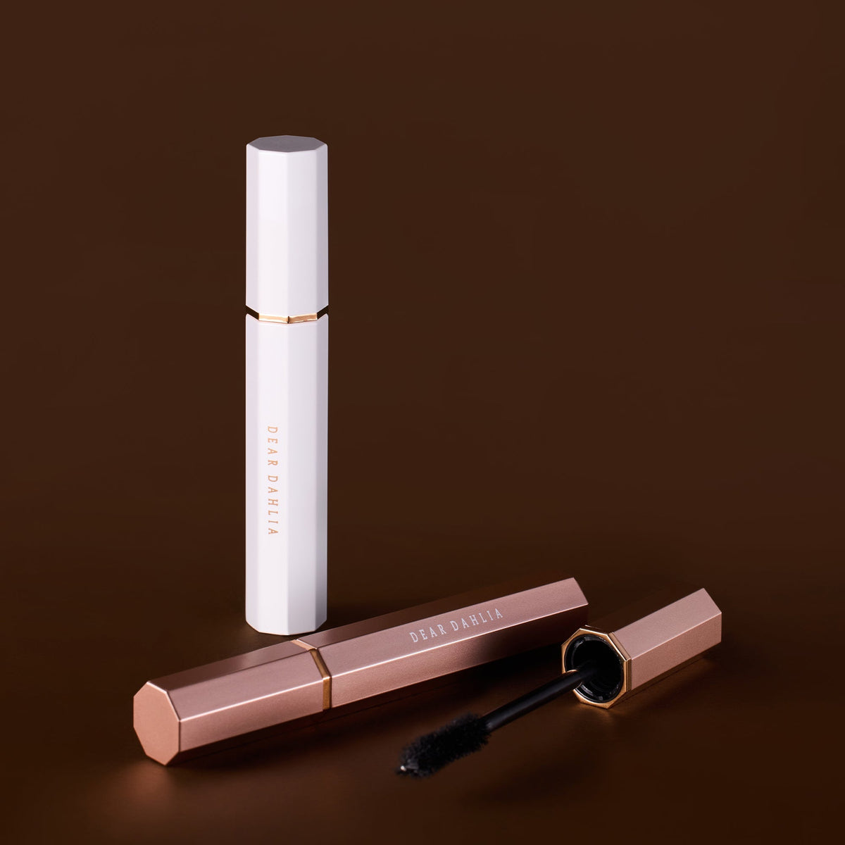 DEAR DAHLIA Paradise Dream Lash Defining Mascara by ProtoClinical shown as a slim brown k-beauty mascara tube on a deep brown background.