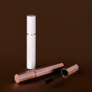 DEAR DAHLIA Paradise Dream Lash Defining Mascara by ProtoClinical shown as a slim brown k-beauty mascara tube on a deep brown background.