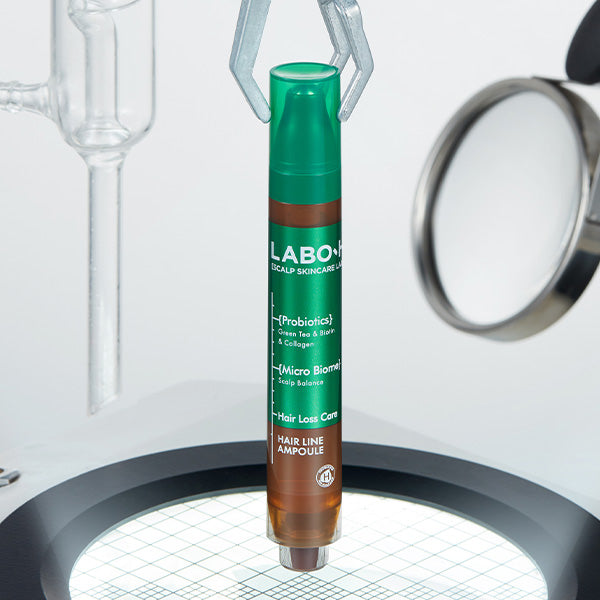 ProtoClinical k-beauty LABO-H Scalp Strengthening Clinic Hair Line Ampoule Hair Loss Care 15ML standing upright in green and brown pen-style packaging on a lit circular platform with glass lab tools