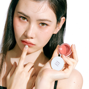ProtoClinical k-beauty HERA Sensual Lip & Cheek 7g model portrait featuring soft nude-pink lip and cheek makeup on a light background.