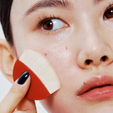 ProtoClinical k-beauty HERA Skin Tint Comfy Spreader SPF50/ PA++++ 15g portrait-style beauty visual on a warm neutral background.