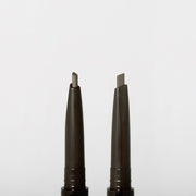 ProtoClinical k-beauty JUNGSAEMMOOL Artist Brow Shader 0.18g two slim gray brow product silhouettes on a white background.