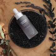 ProtoClinical k-beauty deep charcoal beauty product silhouette on a warm brown background.