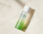 ProtoClinical k-beauty warm beige beauty product detail with soft gray vertical bands on a light background.