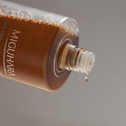 ProtoClinical k-beauty warm brown beauty product detail on a muted gray background.