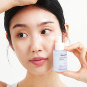 ProtoClinical k-beauty BIODANCE: Hydro Cera-nol Ampoule (30ml) bottle held beside a model's face in a close-up portrait against a light background