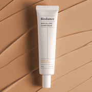 ProtoClinical k-beauty BIODANCE: Skin All-day Cover Balm (30ml) with warm beige packaging, a dark brown vertical center panel, and cream side bands