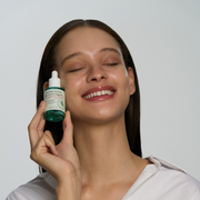 ProtoClinical k-beauty AXIS-Y Artichoke Intensive Skin Barrier Ampoule 30ml close-up brown ampoule bottle with a black dropper cap on a pale aqua background