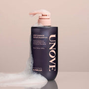 ProtoClinical k-beauty UNOVE DEEP DAMAGE REPAIR SHAMPOO 500ml single upright dark shampoo bottle centered on a soft pink background.