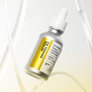 ProtoClinical k-beauty ilso CG Toning Serum 30ml in a beige bottle centered upright on a pale yellow background with soft lavender side bands.