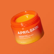 ProtoClinical k-beauty APRILSKIN MINI Carrotene IPMP Hydromelt Cleansing Balm 10ml single orange cleansing balm jar centered on a warm beige background with pale blue side accents.